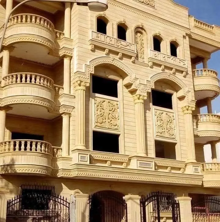 واجهة عمارة من الحجر الهاشمي بأقواس نوافذ كبيرة وبلكونات دائرية
