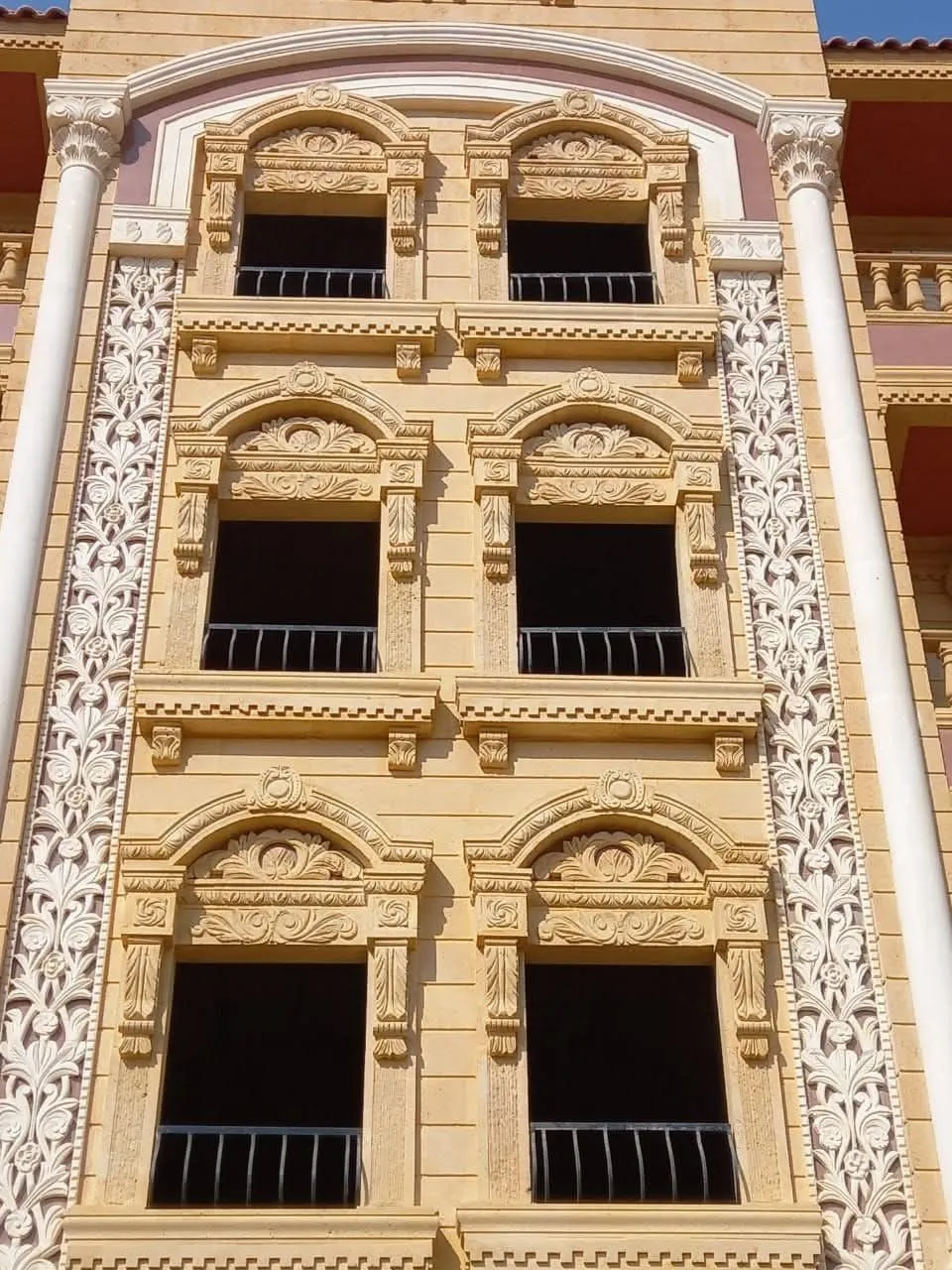 واجهة عمارة من الحجر الهاشمي بنوافذ مقوسة وأشرطة زخرفية